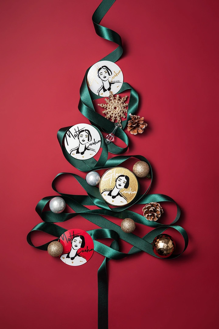 Christmas creative ad: Cushion compacts arranged on ribbon Christmas tree
