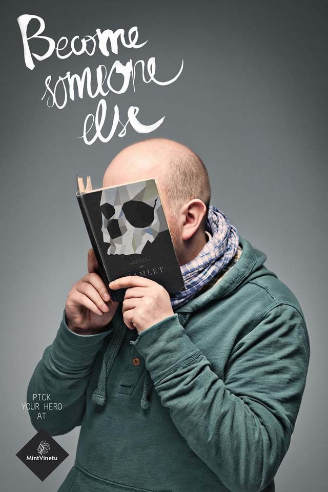 Man holding a skull-covered book over his face like a mask