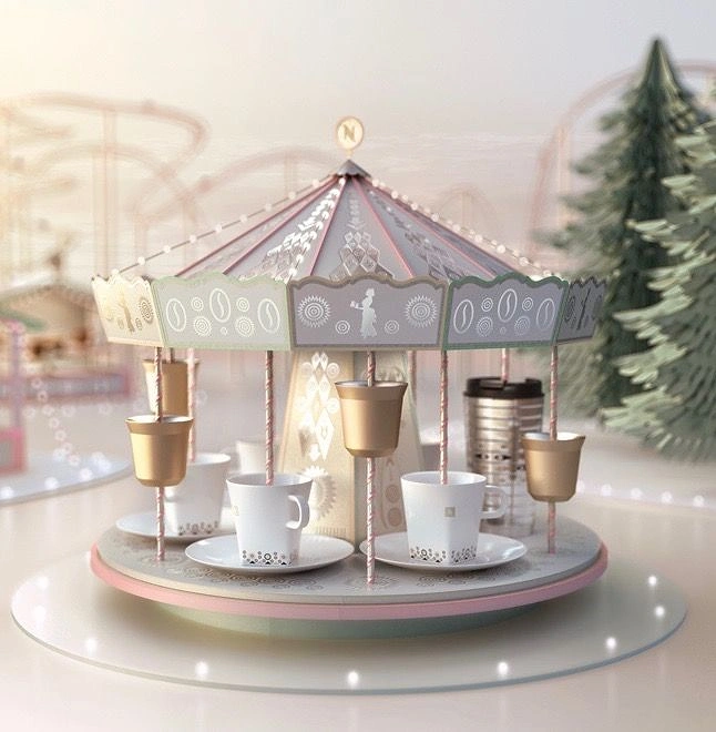 Christmas creative ad: Miniature carousel with coffee cups and gold capsules