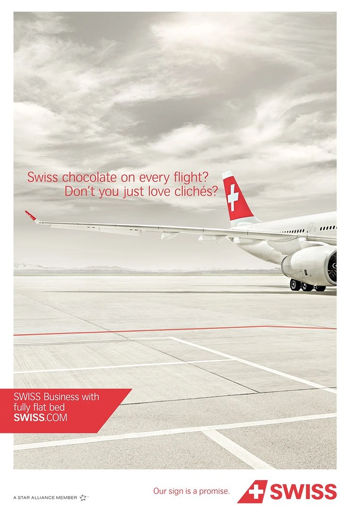 Creative ad: Airliner wing and red-cross tail on an empty desaturated tarmac