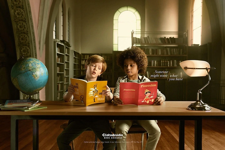 Bookstores creative ad: Two children at a library desk each eyeing the other's book