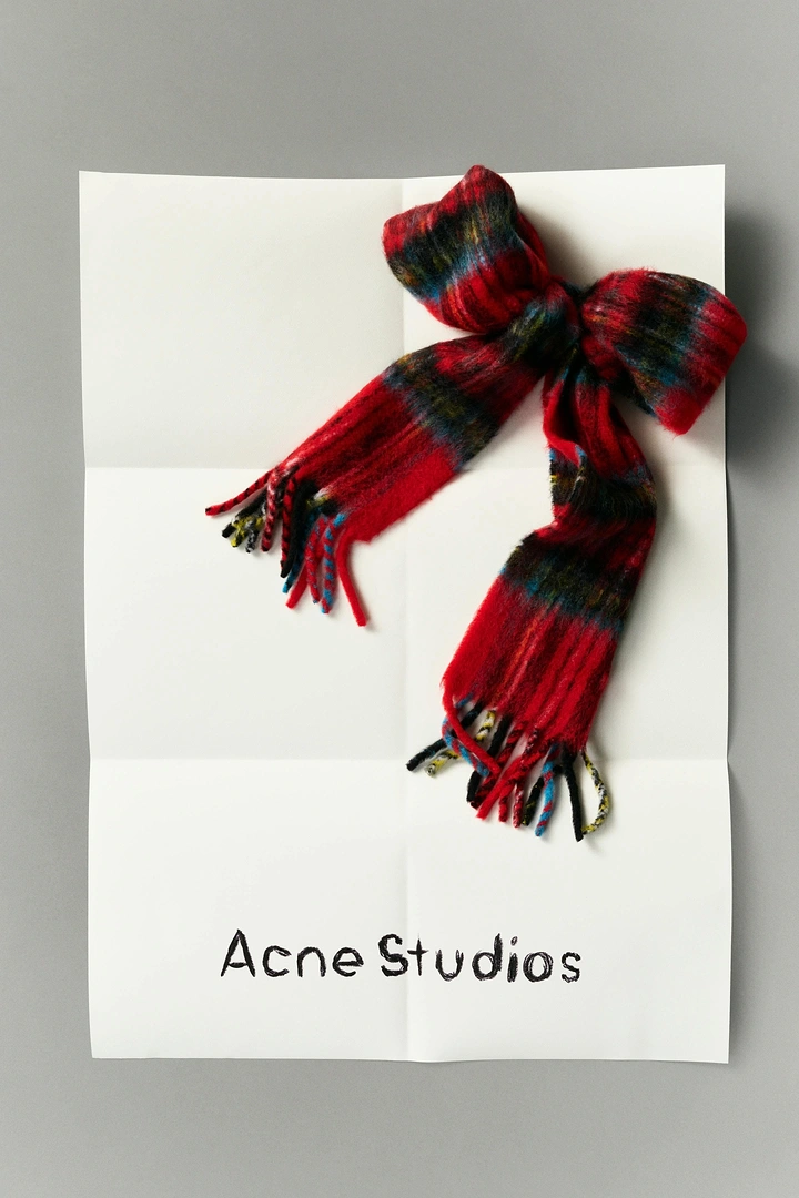 Christmas creative ad: Red plaid mohair scarf tied into a gift bow on a folded paper sheet