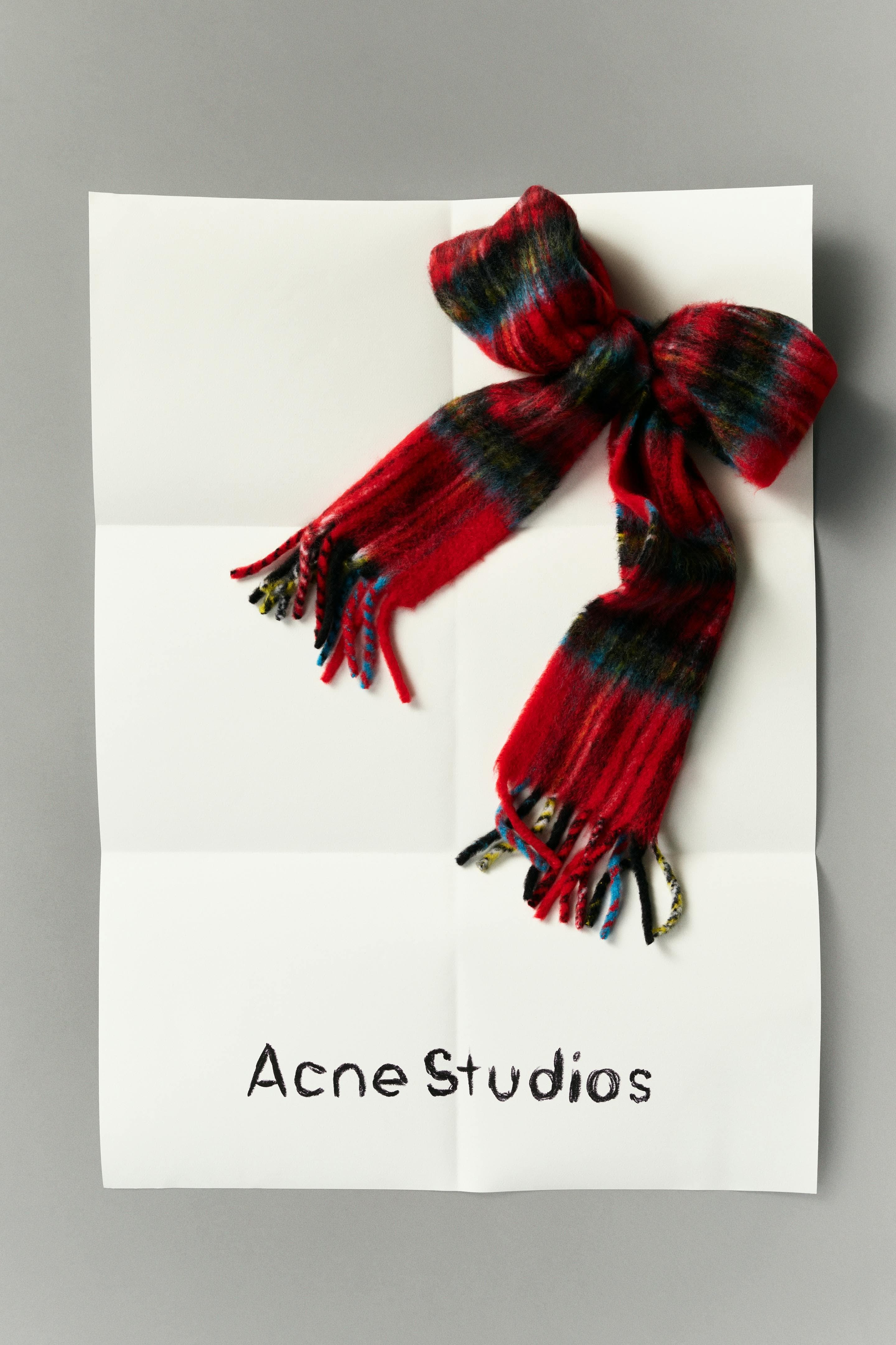 Christmas Poster: Red plaid mohair scarf tied into a gift bow on a folded paper sheet