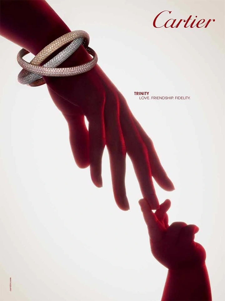Creative ad: Adult hand wearing three pavé bangles reaching to a baby's hand