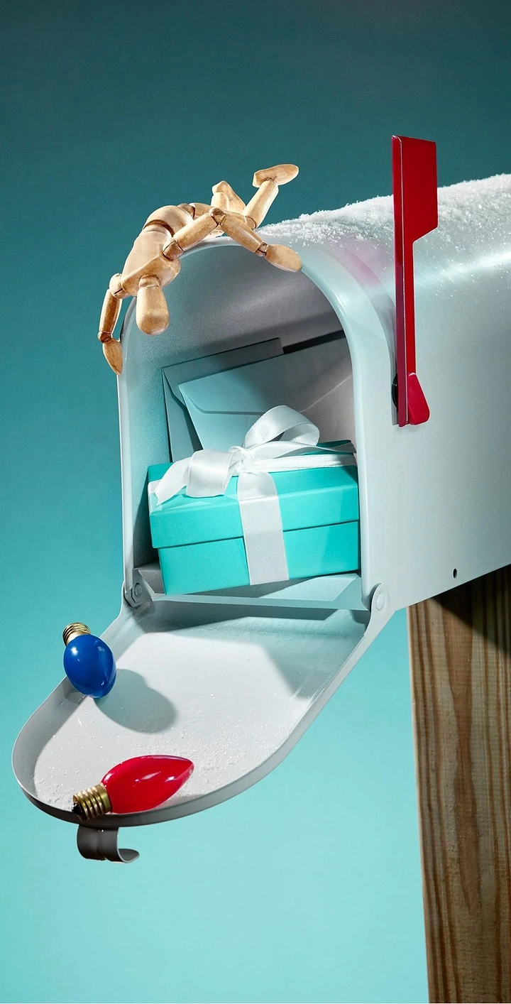 Christmas creative ad: Wooden mannequin peeking into snowy mailbox holding gift