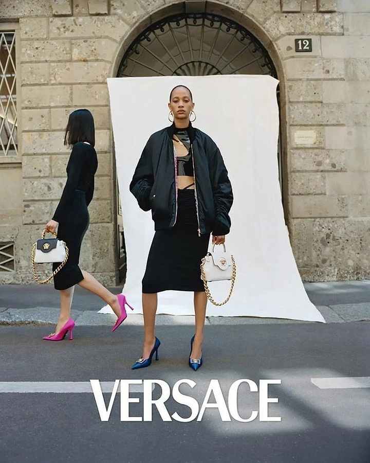Creative ad: Model in black bomber holding white chain handbag on a Milan street