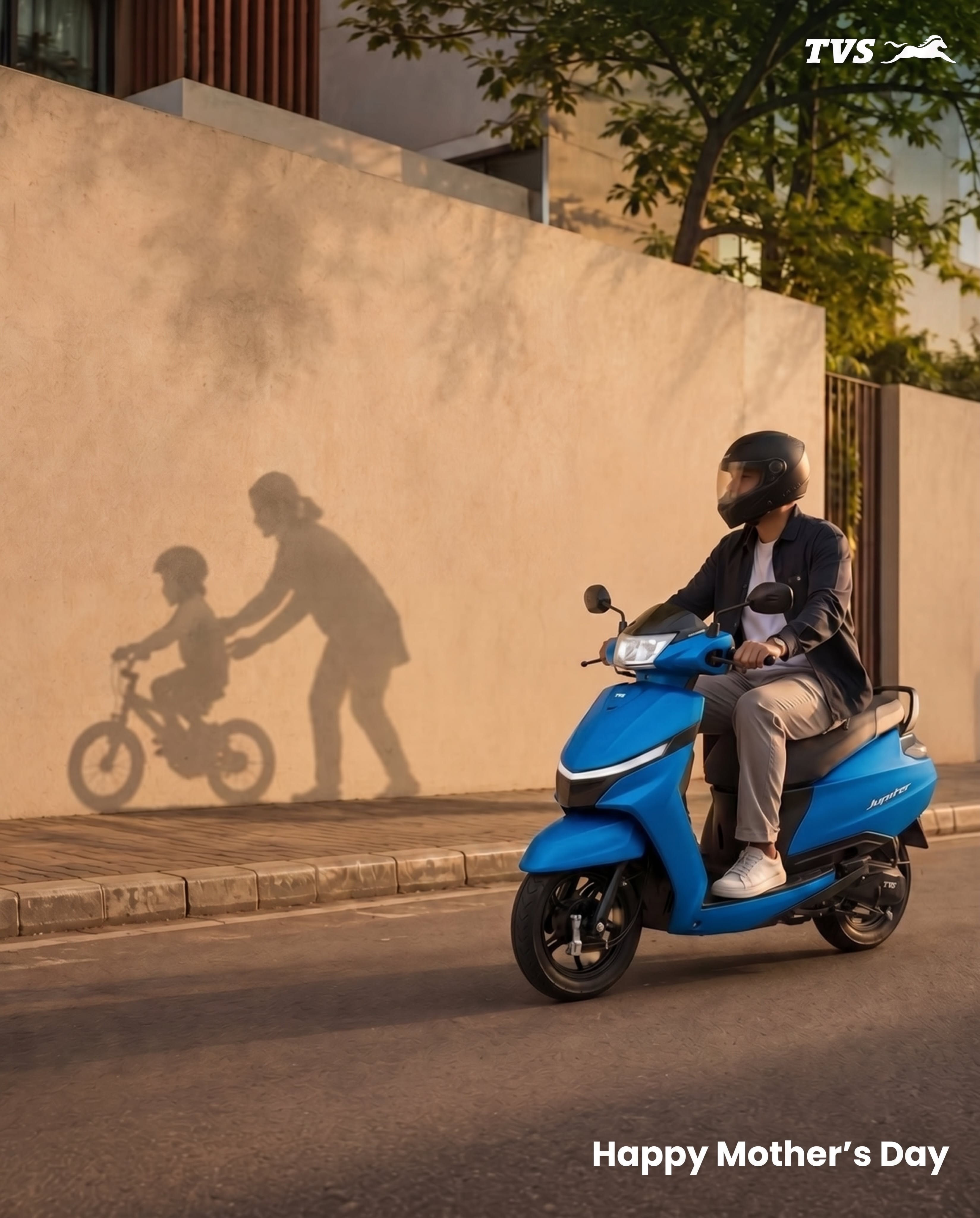 Mother's Day Instagram post: Young man riding a blue scooter past a wall showing the shadow of a mother teaching a child to cycle