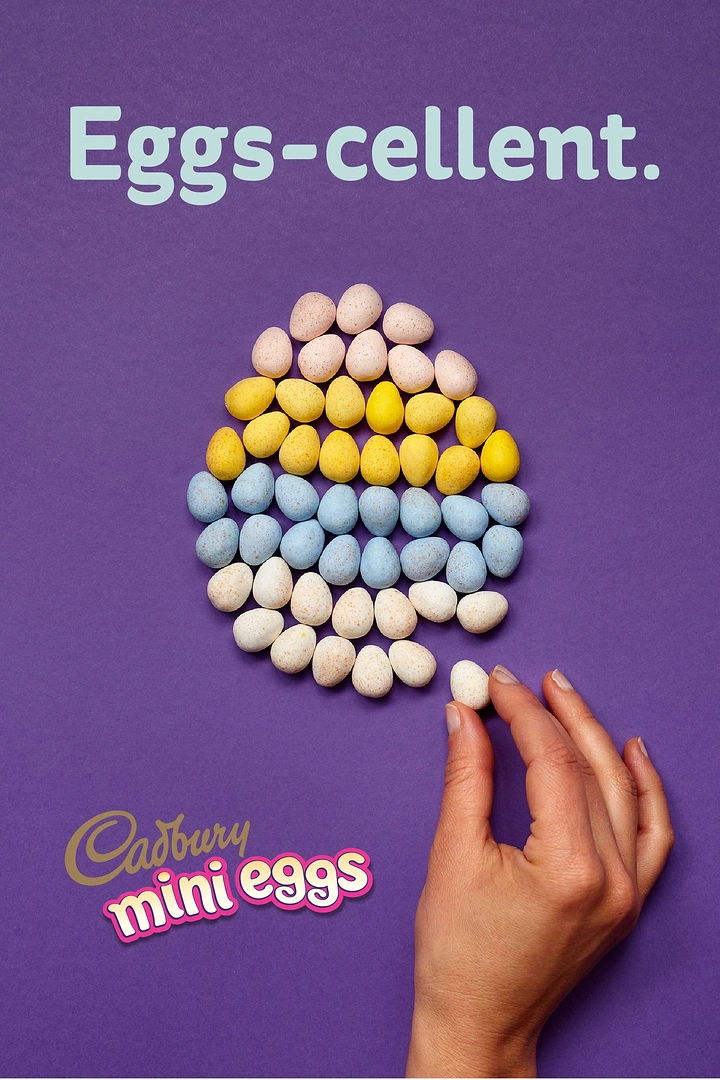 Easter creative ad: Mini candy eggs arranged into a large egg shape, with a hand placing the last one