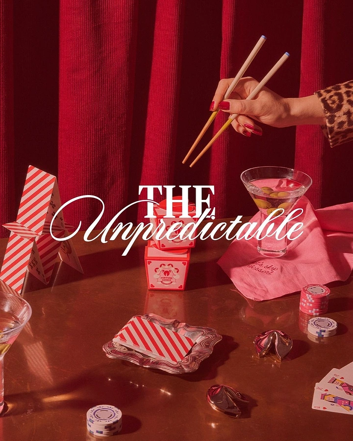 Valentine's Day creative ad: Styled red tabletop with a hand holding chopsticks, martinis and fortune cookies