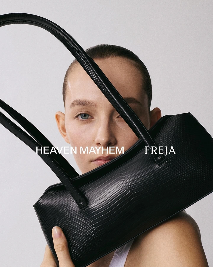 Creative ad: Model holding black croc-effect shoulder bag against her face