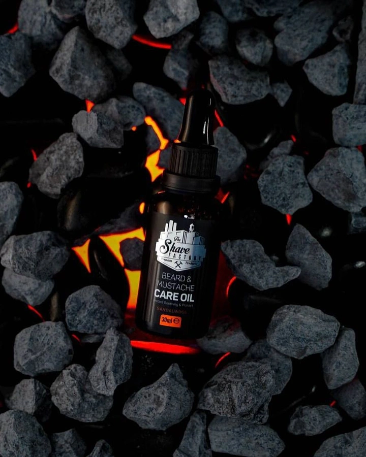 Men's Grooming Brands creative ad: Black beard oil bottle nestled among glowing lava rocks