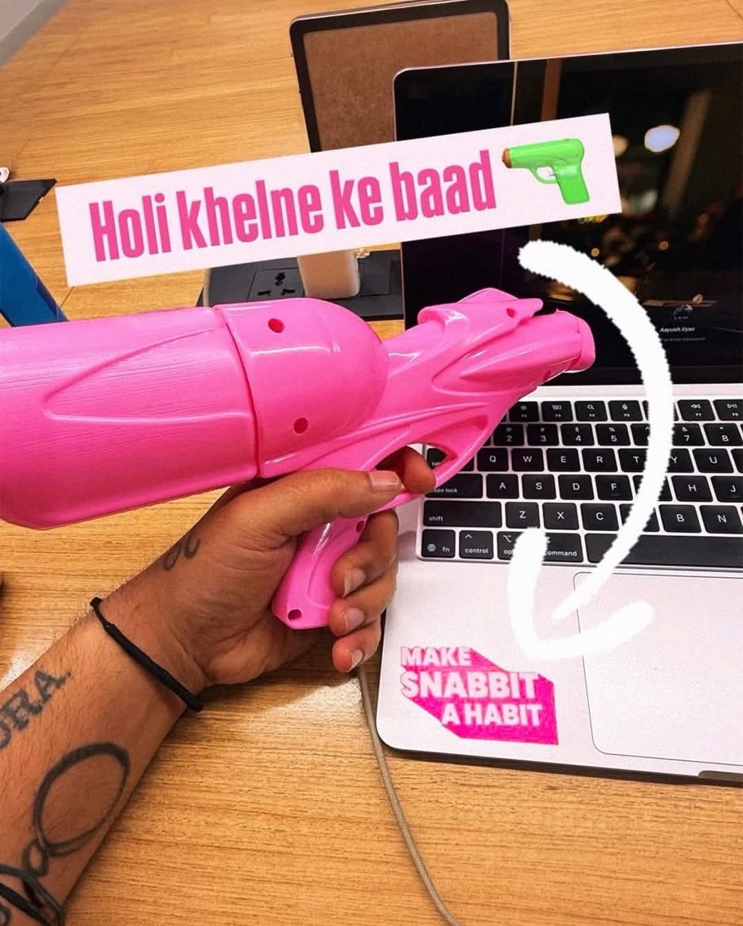 Holi Instagram post: Ornate brass pichkari with a pink condom-like water balloon at its tip, slide 7