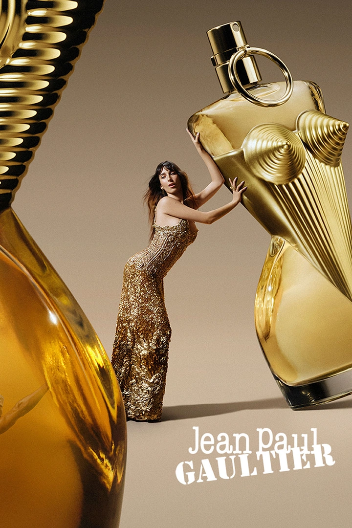Perfume & Fragrance creative ad: Model in gold gown pushing against an oversized gold corset-shaped perfume bottle