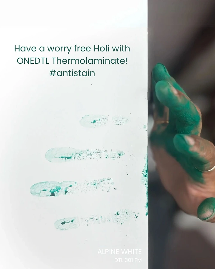 Holi creative ad: Green gulal-covered hand leaving finger marks on a white laminate panel