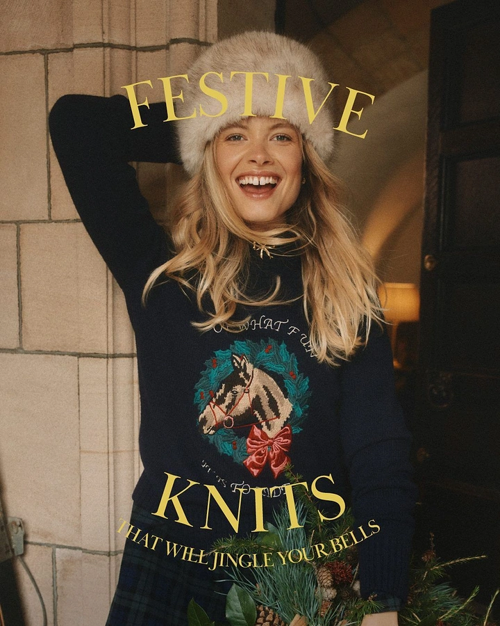 Christmas creative ad: Smiling blonde model in a navy horse-motif knit and fur hat