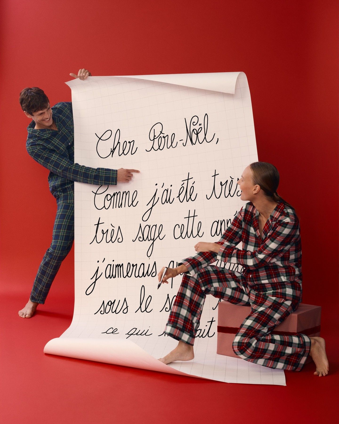 Two models in plaid pyjamas with a giant handwritten letter to Santa