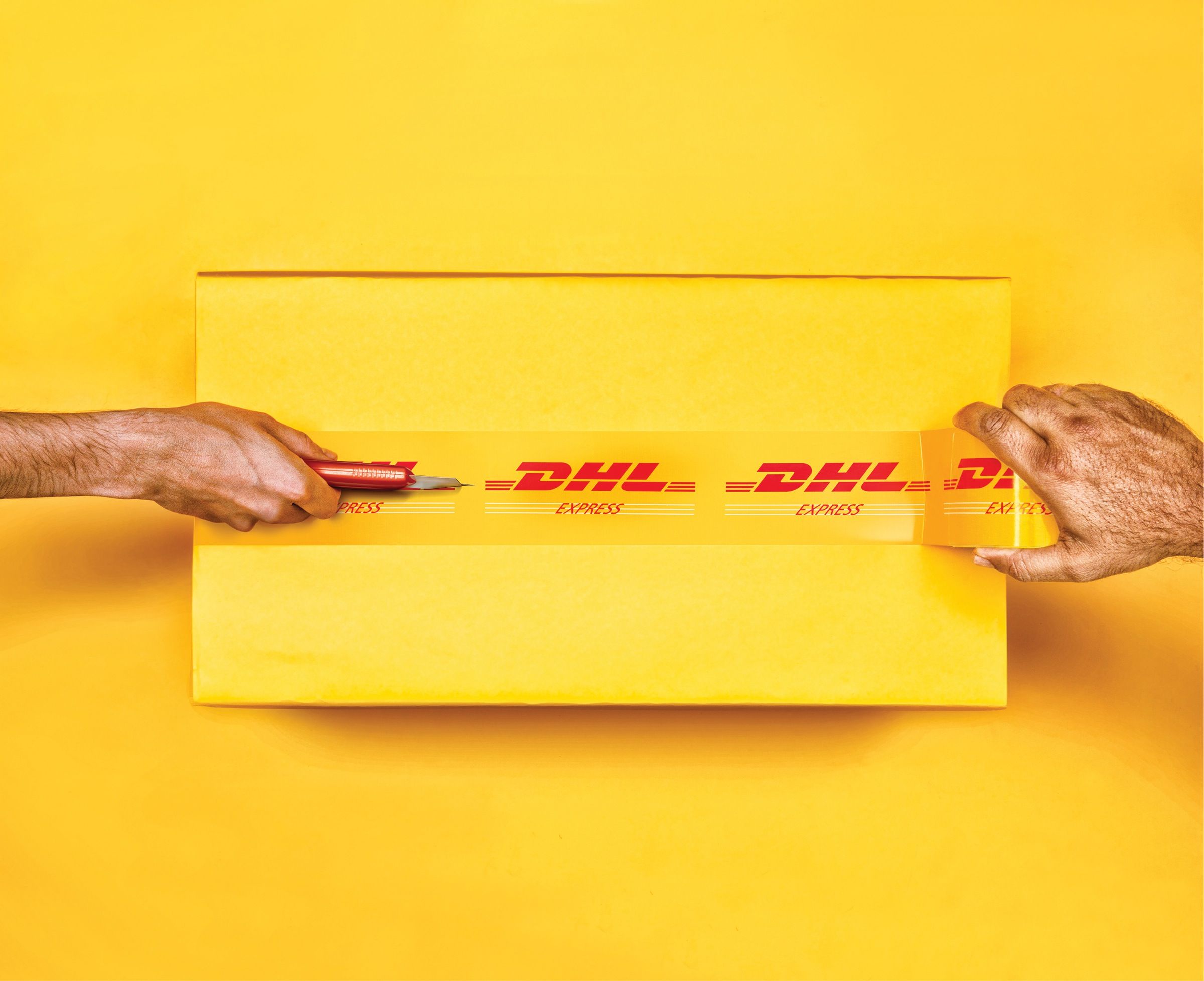 Banner: Hands slicing branded packing tape on a yellow parcel