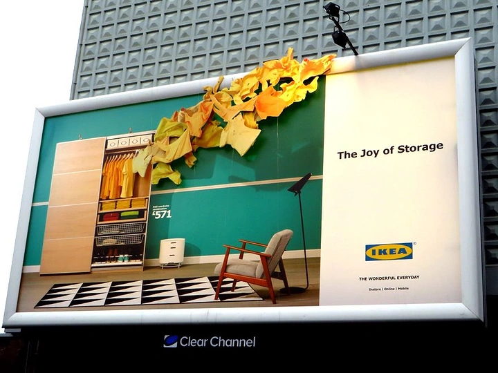 Furniture creative ad: Open wardrobe with yellow clothes bursting beyond the billboard frame